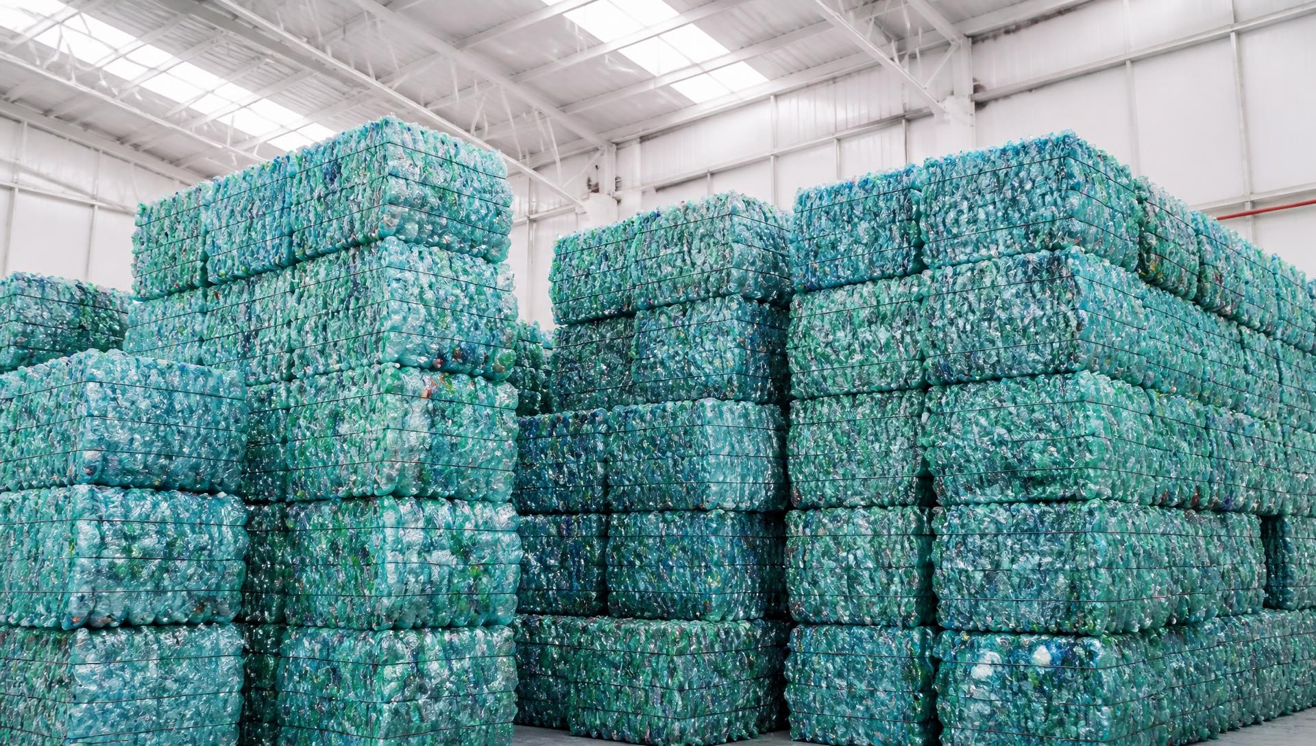 Fardos de material plástico recuperado organizados em galpão industrial